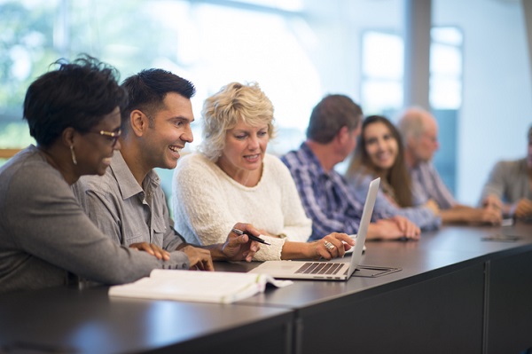 A group of adult students looking at a laptop