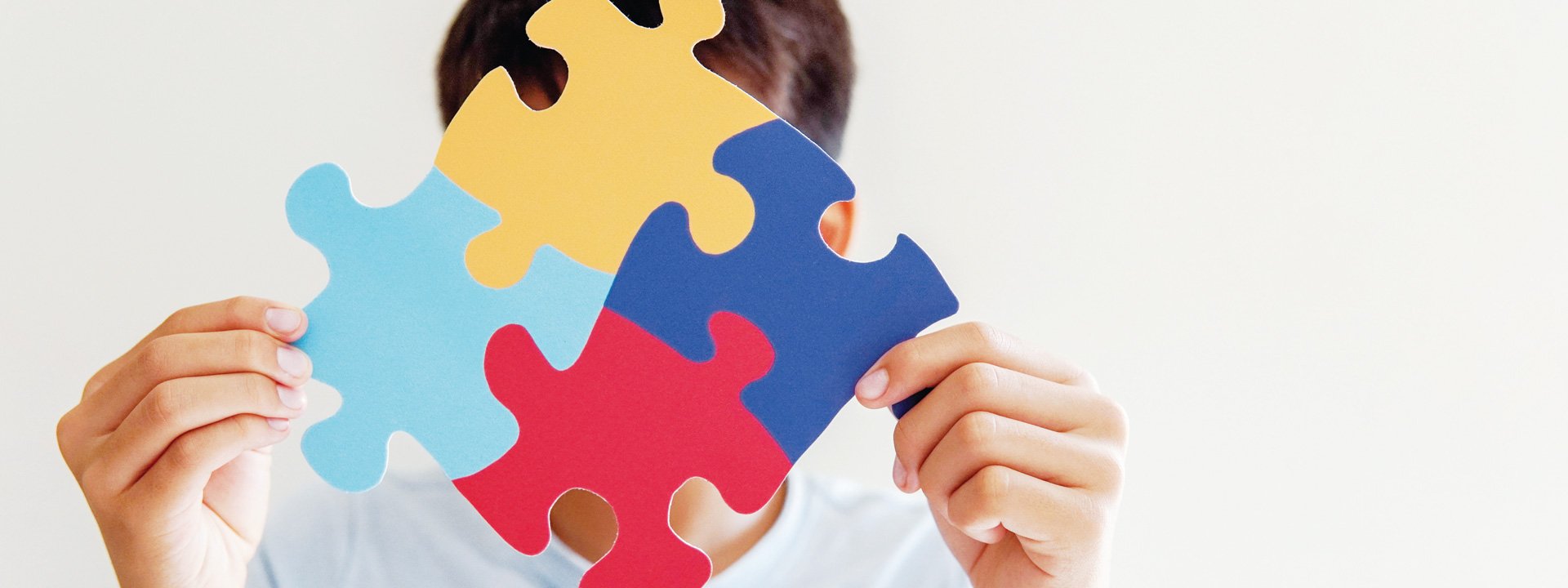 Person holding connected puzzle pieces in front of face