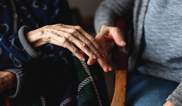 Hand touching an elderly person's hand